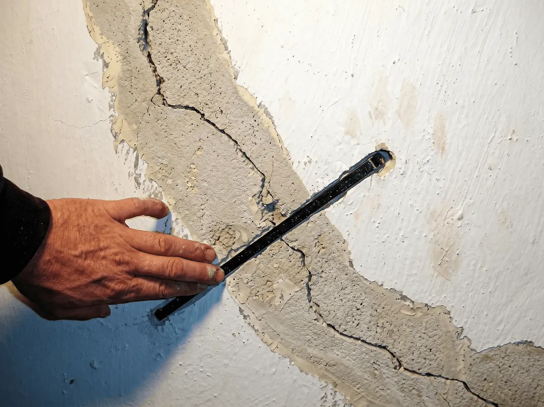 A wall with a large crack is being inspected by a professional in Columbia, SC